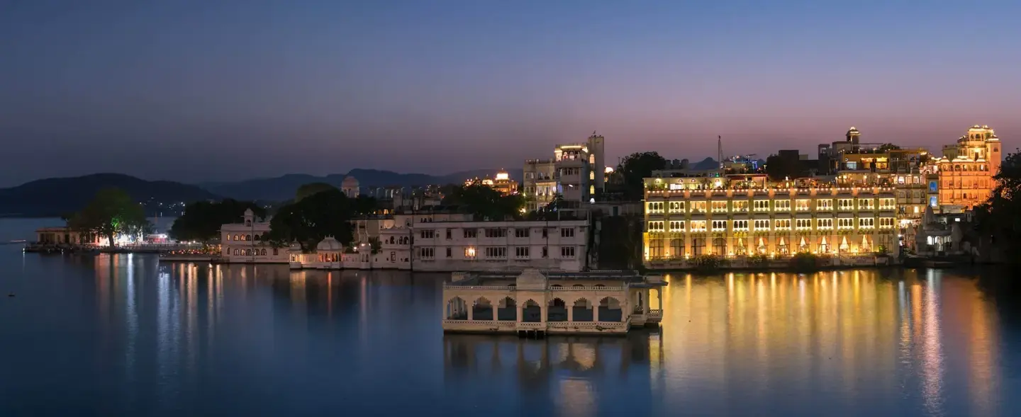 Lake Pichola and City Palace illuminated at night in Udaipur.