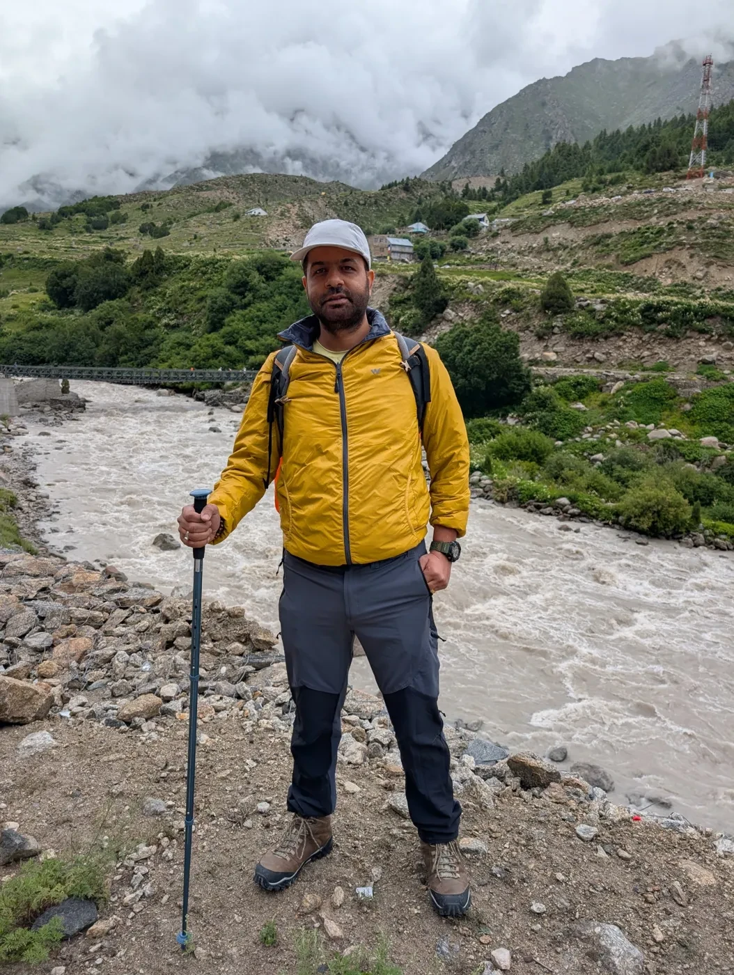 Sunil with a trekking pole beside a mountain river